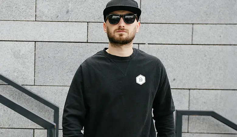 Mann in einem schwarzen Pullover mit minimalistischen JGA-Design, perfekt für den Junggesellenabschied oder Hochzeitsteams.